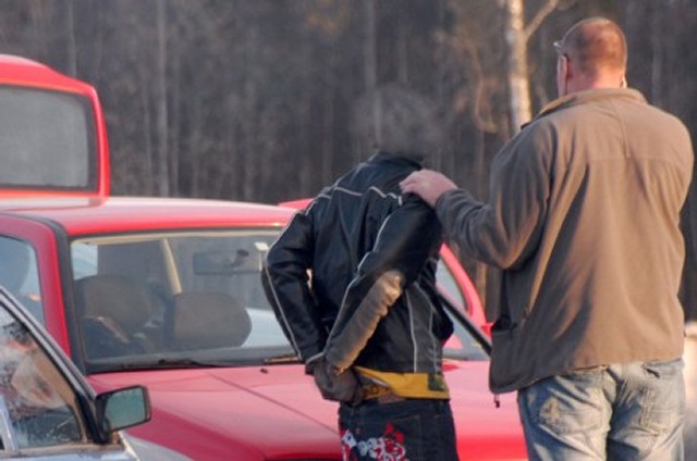 En av gjerningsmennene med hendene bak ryggen i håndjern. (Foto: Romerike Blad)